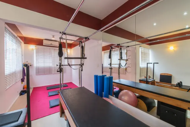 Sala ampla com aparelhos de pilates e espelho