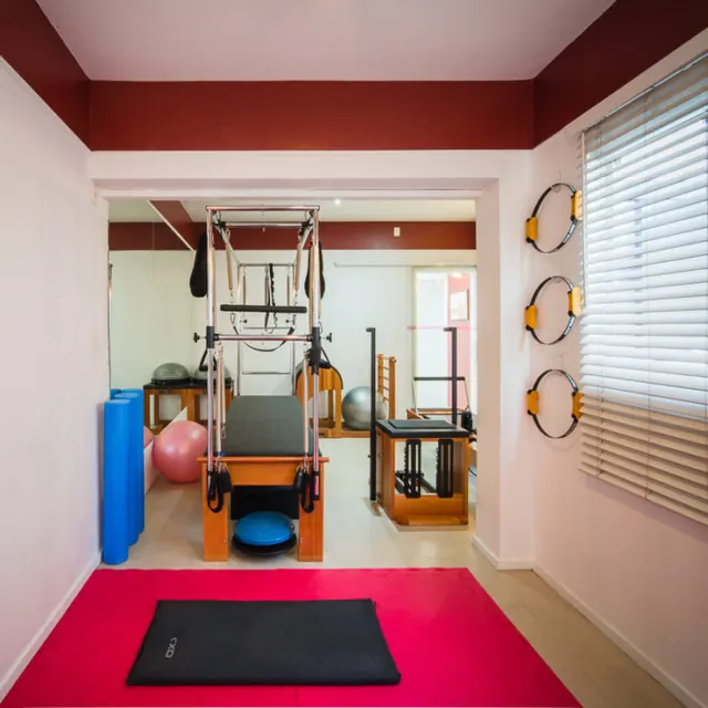 Sala de pilates com cadillac, bolas e tapete vermelho